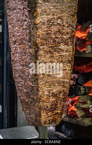 A rotating spit with seasoned lamb slowly cooking by the hot coals at a traditional kebab shop, ready to be shaved for doner kebabs, Istanbul, Turkey Stock Photo