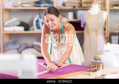 Using ruler, woman tailor draws dress diagram scheme on fabric Stock ...