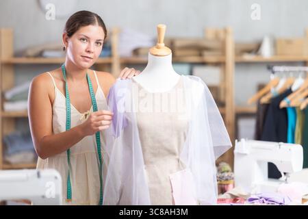 Female dressmaker trying on a dress sample on a mannequin Stock Photo