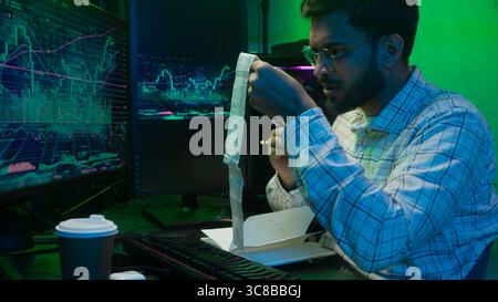 Arabian Indian man male guy programmer examining writing binary code coder freelancer engineer worker IT specialist monitor analyzing computer Stock Photo