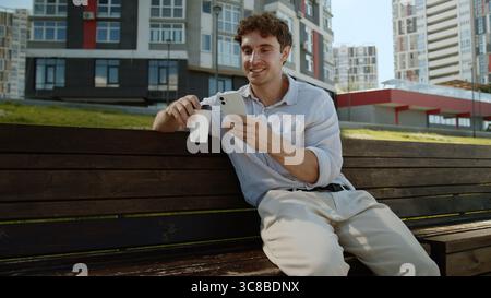 Caucasian man drinking coffee using mobile phone smartphone cellphone online employee entrepreneur internet social media funny smile businessman male Stock Photo