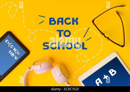 Bright back to school setup with school supplies, gadgets, and accessories on vibrant yellow background Stock Photo