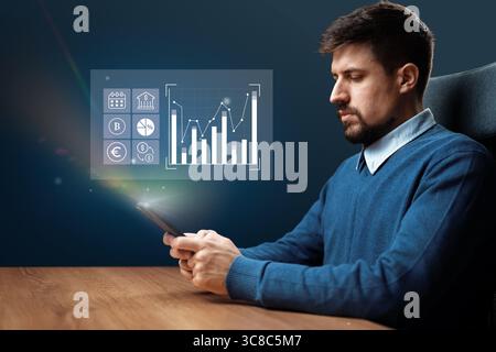 Professional man analyzing financial data on smartphone with charts and graphs displayed in a modern office setting Stock Photo