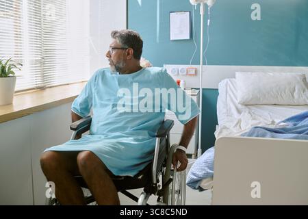 Middle Aged Biracial Man with Disability Sitting in Wheelchair Looking Away Stock Photo