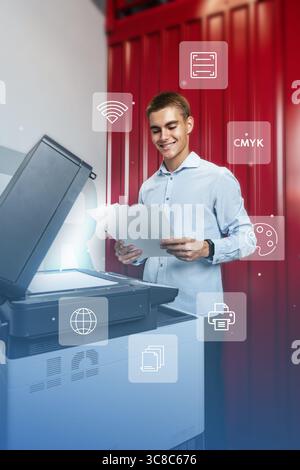Young man smiling while using a multifunction printer for printing documents in a modern workspace Stock Photo