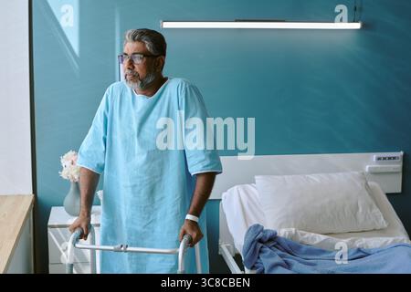 Middle Aged Biracial Man Using Walker Recovering in Hospital Room Stock Photo