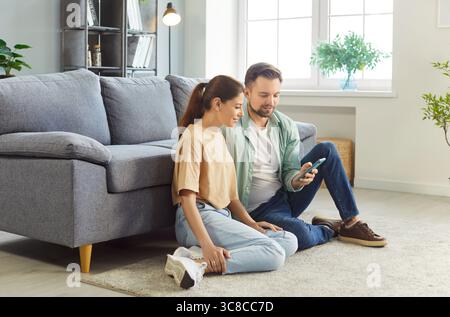 Young couple sitting on floor using smart phone together at home Stock Photo
