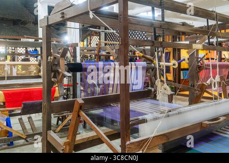 Colorful silk threads on loom and wooden handlooms in traditional silk factory, Chiang Mai, Thailand. Handmade craftsmanship, artistry of textile Stock Photo