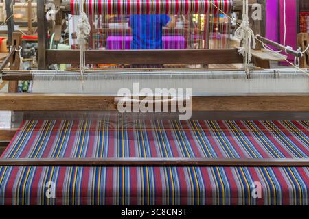 Colorful silk threads on loom and wooden handlooms in traditional silk factory, Chiang Mai, Thailand. Handmade craftsmanship, artistry of textile Stock Photo