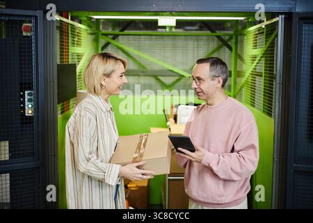 Caucasian Middle Aged Woman Handing Parcel to Caucasian Middle Aged Man Smiling Stock Photo