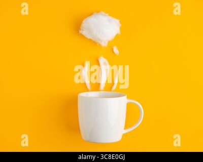 Minimalist concept of a white mug with cotton candy simulating steam placed on a yellow background, representing a hot beverage Stock Photo