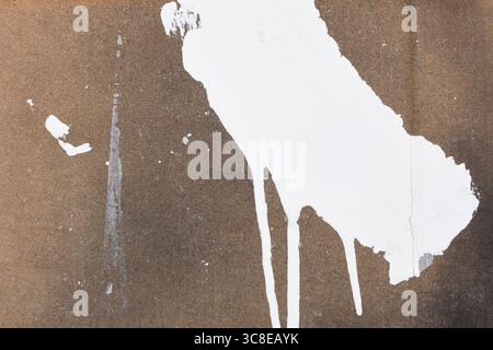 Background with random white paint strokes and drips on brown cardboard with splashes of black paint Stock Photo