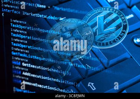 Information technology concept. Coding programmer language script text on screen monitor display with a PC keyboard and bitcoin, ethereum and litecoin Stock Photo