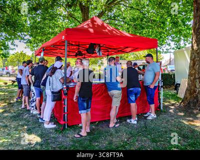 Group of people drinking at beer tent under shade of trees on hot Summer day - Paulmy, Indre-et-Loire (37), France. Stock Photo