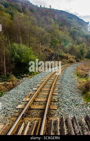 A train track cutting through the woodlands of Eryri National Park in Wales, in the early Autumn. Stock Photo