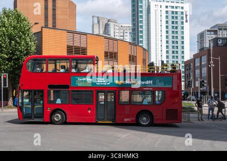Tourists riding on a Cardiff Sightseeing bus, half open-topped hop on hop off red bus in the city centre, Cardiff, Wales, UK Stock Photo