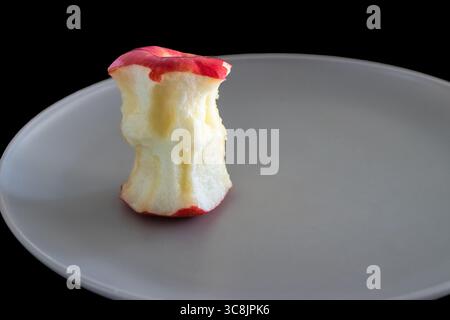 A bitten red apple on a grey plate with a black background Stock Photo