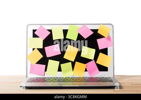 Many blank sticky notes covering a laptop screen on wooden table against isolated white background. Concept of deadlines or ideas Stock Photo