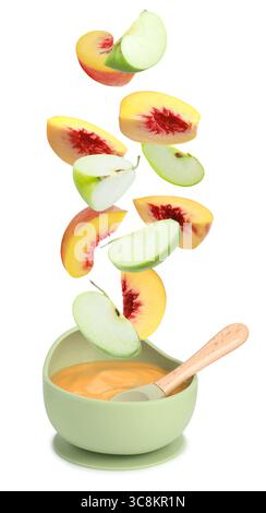 Baby food. Apple and peach slices falling into bowl of puree on white background Stock Photo