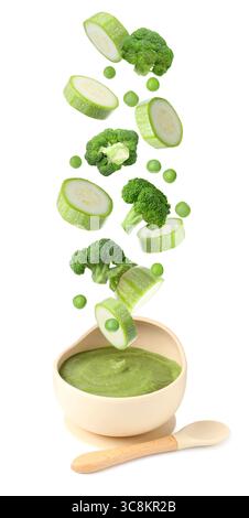 Baby food. Zucchini slices, broccoli and green peas falling into bowl of puree on white background Stock Photo