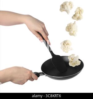 Woman tossing cauliflower while frying it in wok against white background, closeup Stock Photo