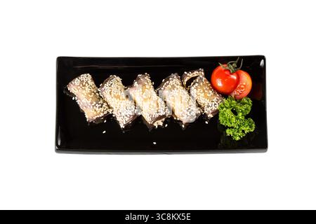 Eggplant rolls with cheese, garlic and sesame on black plates with herbs and tomato. Top view and isolated on white background. Stock Photo