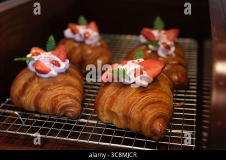 Crispy sweet red croissant with pistachio, raspberry and strawberry on a dark concrete background Stock Photo