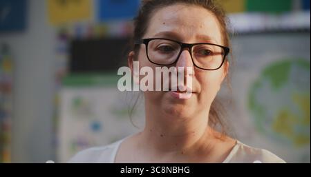 Female Teacher Talking and Conducting Lecture to Students, Teaching School Children Science. Woman Educating Geography, Ecology or Mathematics in Modern Colorful Classroom. Close Up Portrait View. Stock Photo