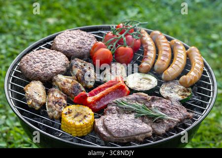 various meats and vegetables on charcoal grill in garden Stock Photo
