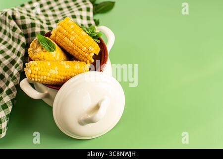 Hot corn cobs with greens on a green background. Stock Photo