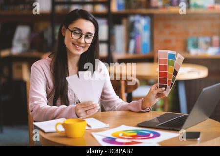 Creative latin woman web-designer working with color palette while sitting at cafe with laptop, free space Stock Photo