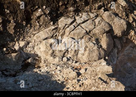 Rocky terrain with uneven surfaces and various textures. Natural geological formations create a rugged landscape. Earthy tones dominate scene Stock Photo