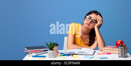Tired indian woman in glasses sitting at desk reading book Stock Photo ...