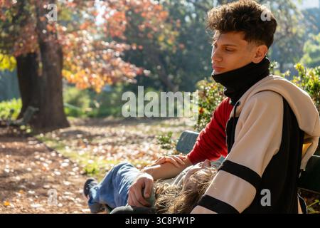 Romantic couple relaxing on park bench in fall, enjoying peaceful moment together Stock Photo