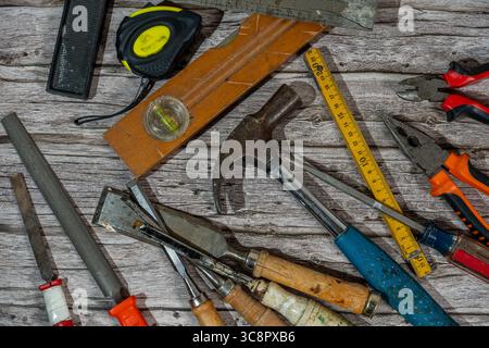 Various carpentry tools lying on wooden workbench top view showing hammer, tape measure, pliers and other tools Stock Photo