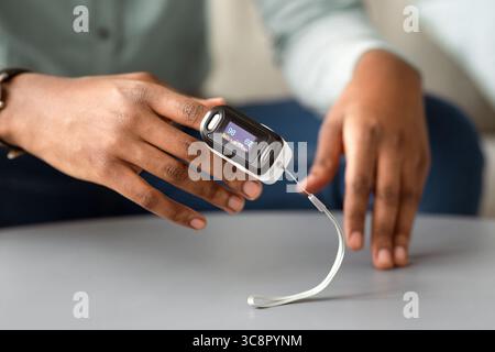 Unrecognizable African Man Using Pulse Oximeter Checking Oxygen Saturation Indoor Stock Photo