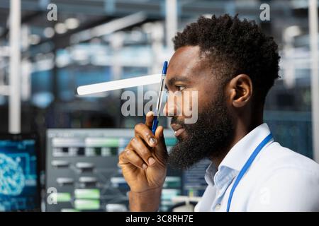 Close up of server hub worker doing brainstorming, troubleshooting errors. African american data center computer scientist monitoring system performance with laptop, identifying bottlenecks Stock Photo