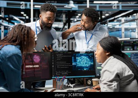 Technicians in AI server hub brainstorm ways to defend against hacker attack stealing sensitive data. Data center coworkers discussing how to protect gear against virus during security breach Stock Photo