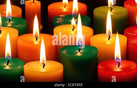 Bright multicolored burning candles close-up in the dark, colorful background Stock Photo