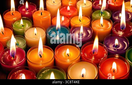 Close-up of bright multicolored burning candles in the dark, bright colorful background Stock Photo