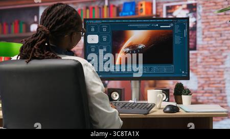 Woman using AI program turning text prompt into videos, pleased by results. Person surrounded by plants interacting with text to video artificial intelligence generative model, camera B Stock Photo
