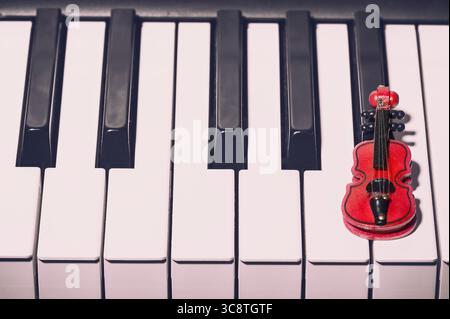 Music concept. Red decorative violin on the piano. Stock Photo