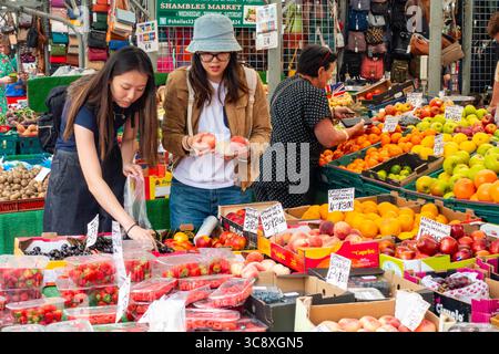 A couple of ladies choosing fruit at a greengrocer's stall in The Shambles Market in York, UK Stock Photo