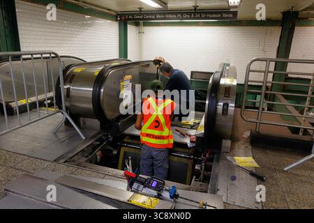 NYC Transit Elevator and Escalator Maintainers "mechanics" repair an escalator at the Times Square station in the NYC Subway, New York City. Stock Photo