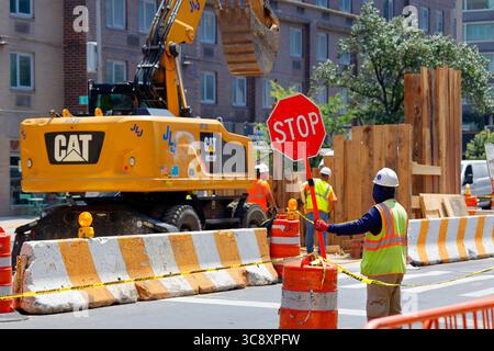 A traffic controller, or construction flagger, holding a stop sign at a road construction work zone in New York City. Stock Photo