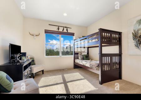 This is a cozy bedroom featuring a bunk bed along with a television Stock Photo