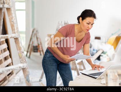 Woman construction manager checking project documentation, using laptop Stock Photo