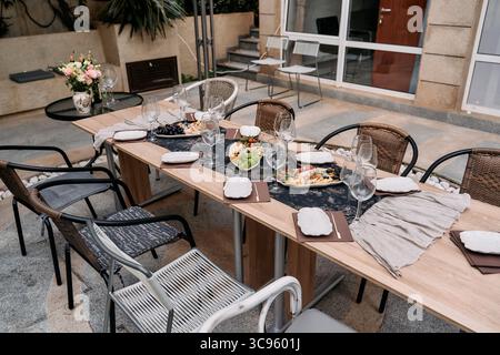 Elegant Outdoor Dining Setup Featuring a Beautifully Arranged Table with Gourmet Dishes, Glassware, and Floral Centerpiece for an Enchanting Culinary Stock Photo
