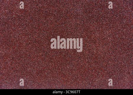 Close-up texture of red granular roofing surface with mineral coating for waterproofing, durability Stock Photo