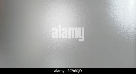 Close up, textured blurred frosted glass. Color is a light, cool gray with bright white highlights where the light source hits, creating a sense of de Stock Photo